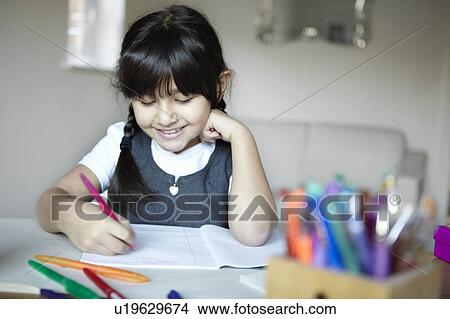 Picture - Schoolgirl writing at desk. Fotosearch