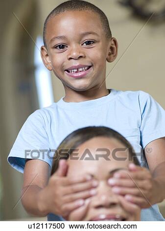 Smiling boy covering mothers eyes View Large Photo Image Stock Image - Smiling boy covering mothers eyes. Fotosearch