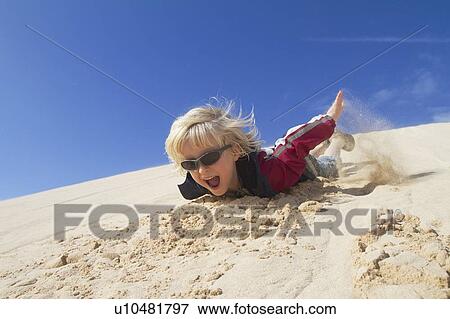 Smiling boy sliding down sand dune View Large Photo Image Stock Photo - Smiling boy sliding down sand dune. Fotosearch