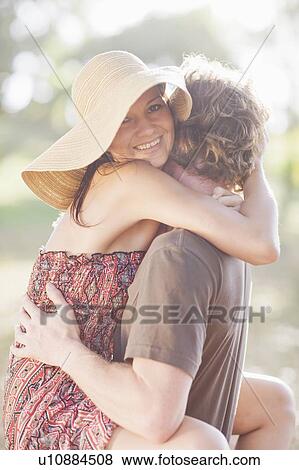 Stock Photo - Smiling couple hugging in field. Fotosearch