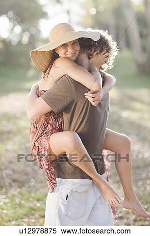 Stock Photography - Smiling couple hugging in field. Fotosearch