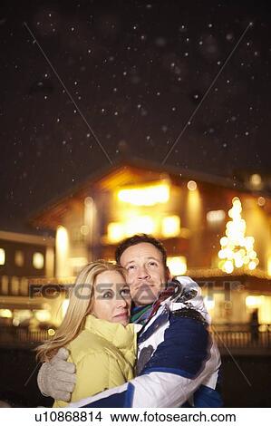 Picture - Smiling couple hugging in snow. Fotosearch