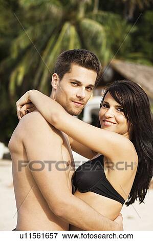 Stock Photo - Smiling couple hugging on beach. Fotosearch