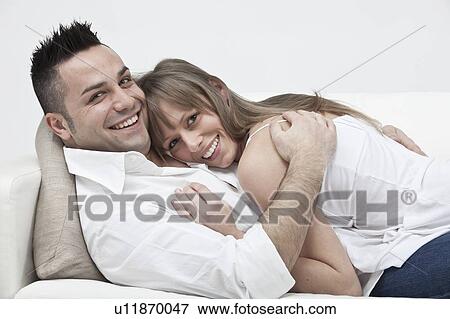 Stock Photo - Smiling couple hugging on couch. Fotosearch