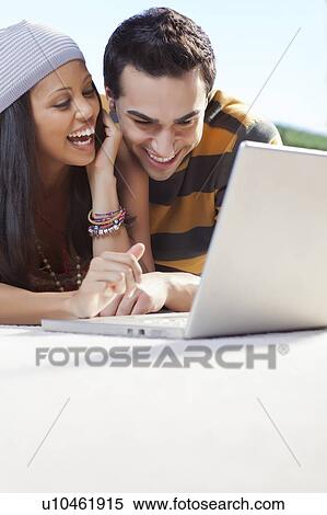 Stock Photography - Smiling couple using laptop outdoors. Fotosearch