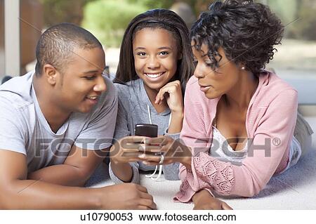 Smiling family using cell phone together View Large Photo Image Stock Image - Smiling family using cell phone together. Fotosearch