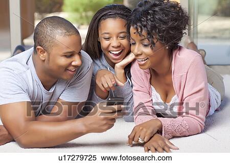 Smiling family using cell phone together View Large Photo Image Stock Photography - Smiling family using cell phone together. Fotosearch
