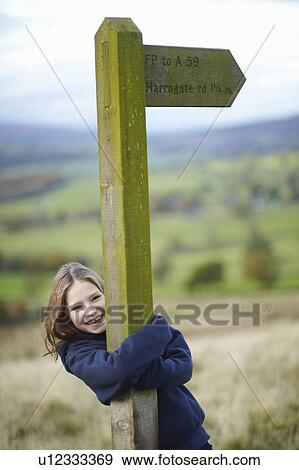 Smiling girl hugging road sign View Large Photo Image Stock Photo - Smiling girl hugging road sign. Fotosearch