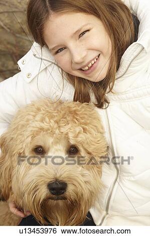 Stock Photograph - Smiling girl petting dog outdoors. Fotosearch