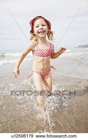 Stock Photo - Smiling girl playing in waves on beach. Fotosearch