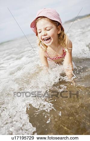 Stock Photo - Smiling girl playing in waves on beach. Fotosearch