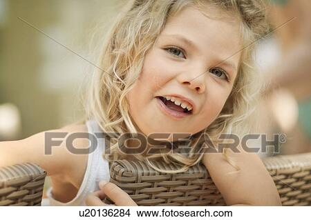 Picture - Smiling girl sitting in wicker chair. Fotosearch
