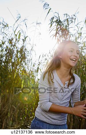 Stock Photograph - Smiling girl walking in wheatfield. Fotosearch
