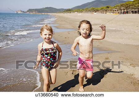Smiling girls playing in waves on beach View Large Photo Image Stock Image - Smiling girls playing in waves on beach. Fotosearch
