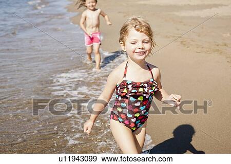 Smiling girls playing in waves on beach View Large Photo Image Stock Photo - Smiling girls playing in waves on beach. Fotosearch