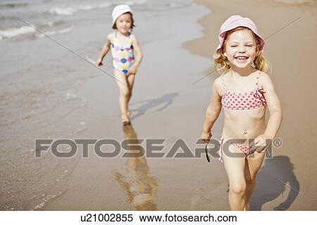 Smiling girls walking in waves on beach View Large Photo Image Stock Photography - Smiling girls walking in waves on beach. Fotosearch