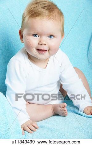 Stock Photo - Smiling infant sitting on blue blanket. Fotosearch