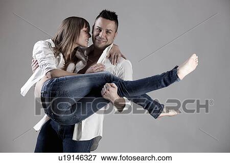 Stock Photo - Smiling man carrying girlfriend. Fotosearch
