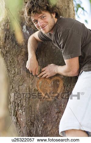 Smiling man carving heart in tree View Large Photo Image Stock Photo - Smiling man carving heart in tree. Fotosearch