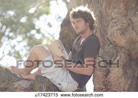 Smiling man reading in tree View Large Photo Image Stock Photography - Smiling man reading in tree. Fotosearch