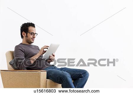 Stock Image - Smiling man using tablet computer. Fotosearch