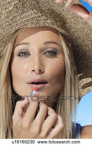 Smiling woman applying lipstick outdoors View Large Photo Image Stock Image - Smiling woman applying lipstick outdoors. Fotosearch