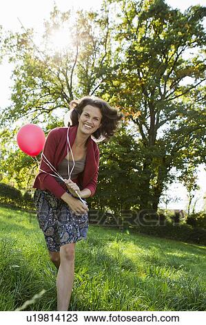 Smiling woman carrying balloons View Large Photo Image Stock Image - Smiling woman carrying balloons. Fotosearch
