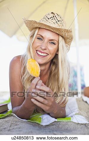 Smiling woman eating popsicle on beach View Large Photo Image Stock Image - Smiling woman eating popsicle on beach. Fotosearch