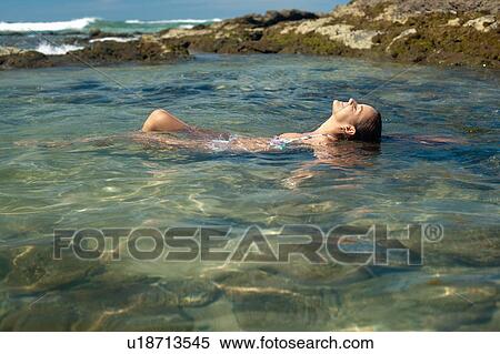 Stock Photography - Smiling woman floating in lake. Fotosearch