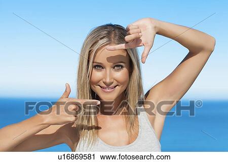 Stock Image - Smiling woman framing her face. Fotosearch