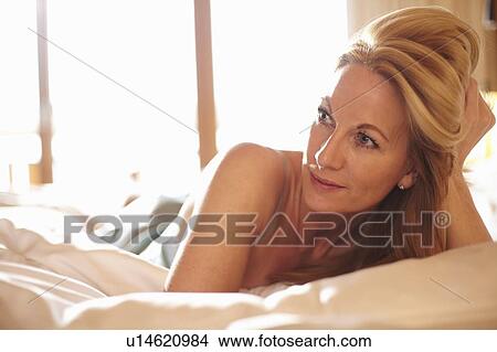 Smiling woman laying on bed View Large Photo Image Picture - Smiling woman laying on bed. Fotosearch