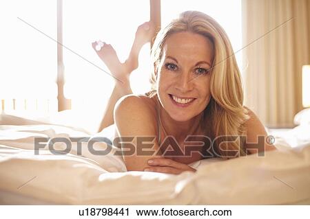 Smiling woman laying on bed View Large Photo Image Stock Image - Smiling woman laying on bed. Fotosearch