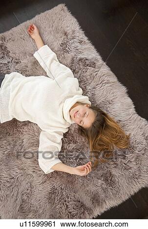 Stock Image - Smiling woman laying on rug. Fotosearch