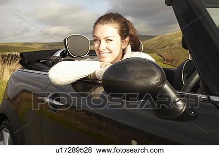 Stock Photo - Smiling woman leaning out of convertible. Fotosearch