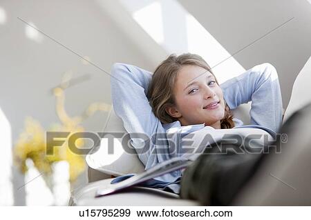 Stock Photo - Smiling woman relaxing on sofa. Fotosearch