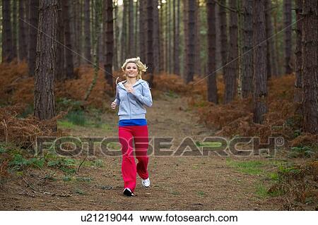 Picture - Smiling woman running in woods. Fotosearch