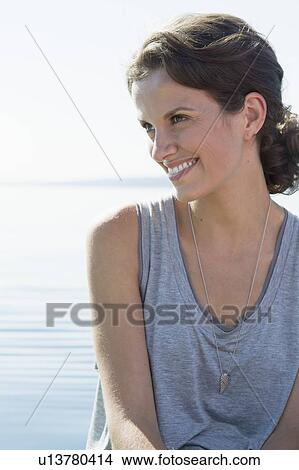 Smiling woman sitting by water View Large Photo Image Picture - Smiling woman sitting by water. Fotosearch