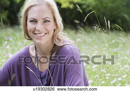 Smiling woman sitting in wheatfield View Large Photo Image Stock Photograph - Smiling woman sitting in wheatfield. Fotosearch