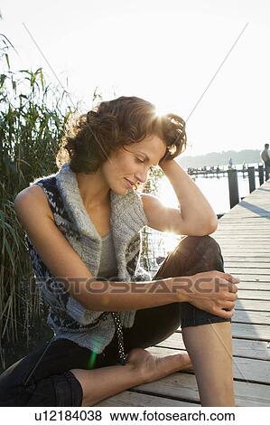 Stock Photo - Smiling woman sitting on pier. Fotosearch