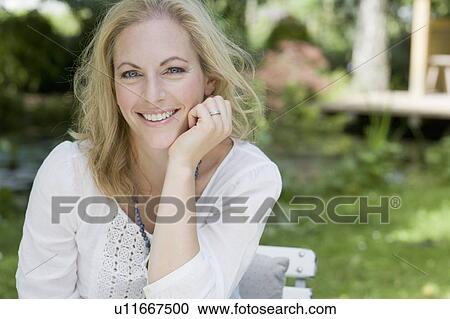 Stock Image - Smiling woman sitting outdoors. Fotosearch