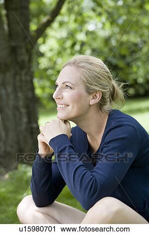 Stock Image - Smiling woman sitting outdoors. Fotosearch