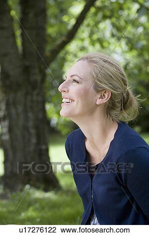 Stock Image - Smiling woman sitting outdoors. Fotosearch