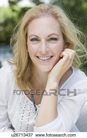 Stock Photo - Smiling woman sitting outdoors. Fotosearch