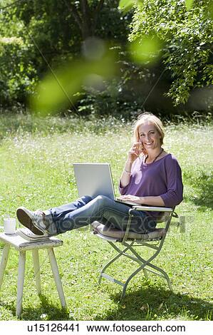 Smiling woman using laptop outdoors View Large Photo Image Stock Image - Smiling woman using laptop outdoors. Fotosearch