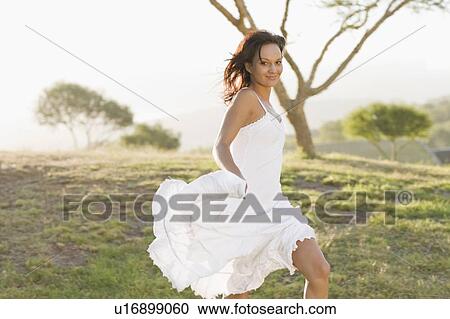 Stock Image - Smiling woman walking in field. Fotosearch