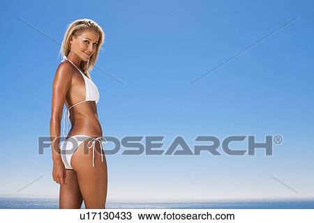Stock Image - Smiling woman wearing bikini outdoors. Fotosearch