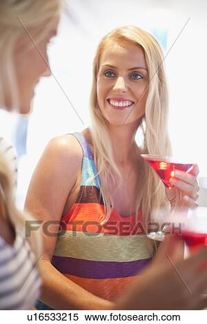 Stock Photography - Smiling women having cocktails together. Fotosearch