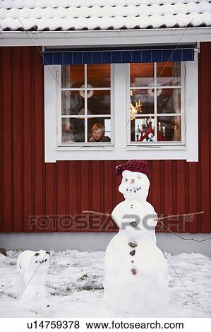 Stock Photo - Snowmen standing outside house. Fotosearch