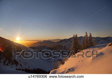 Stock Photograph - Sun setting over snowy landscape. Fotosearch