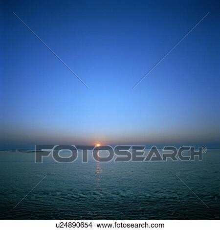 Sun setting over still waters View Large Photo Image Picture - Sun setting over still waters. Fotosearch